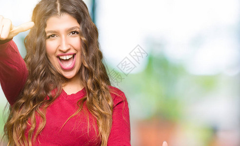 穿着红色毛衣的年轻美女同意用手大拇指微笑图片