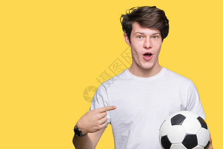 年轻人在孤立的背景下拿着足球惊讶的脸用图片