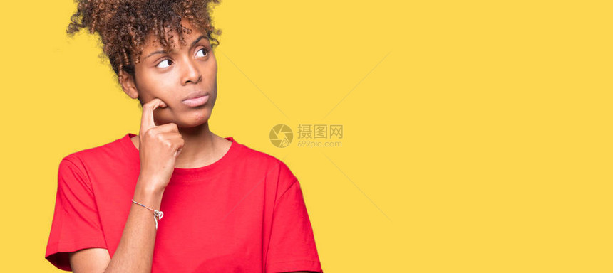 美丽的年轻非洲裔美国女人在孤立的背景下用手托着下巴思考问题图片