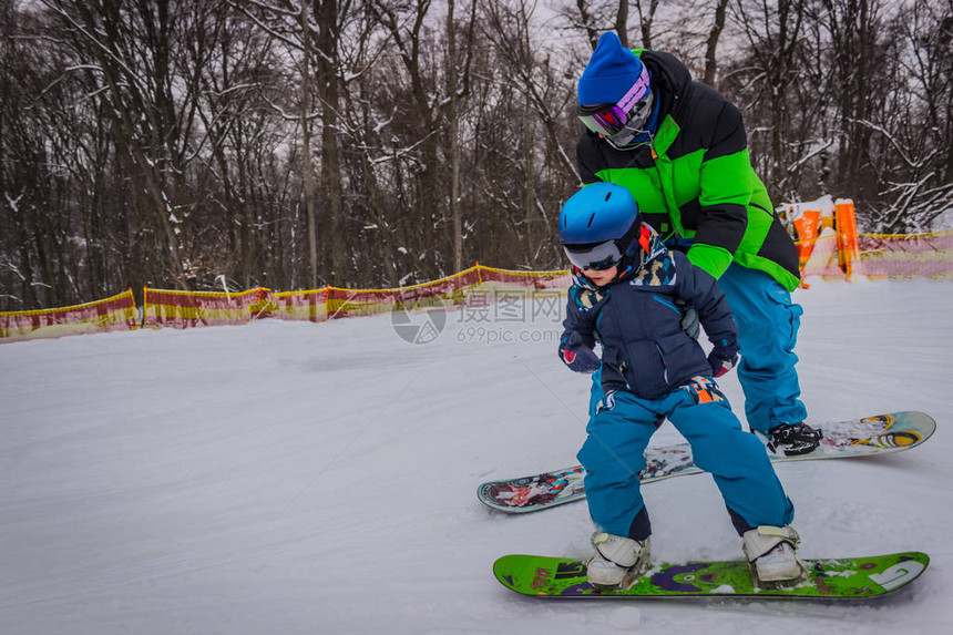 父亲滑雪板教儿子骑在板上图片