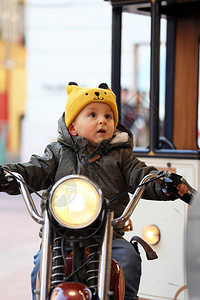 可爱的宝男孩坐在一辆老式摩托车上图片