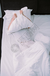 躺在家中床上时用枕头遮面图片