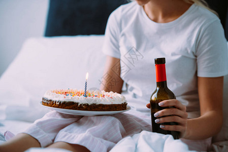 光在床上庆祝生日时用酒瓶和蛋糕图片