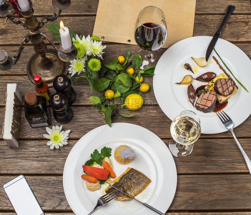 木制餐桌白盘上供应肉类和鱼类菜肴图片