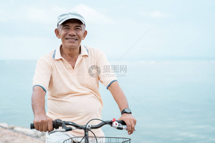 快乐老年男子在海滩骑自图片