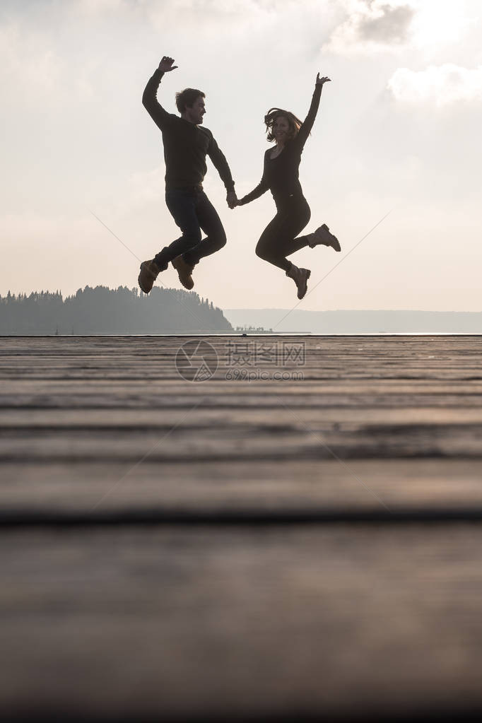 快乐的一对年轻夫妇手牵从木头图片