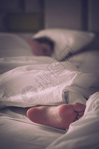 妇女赤脚躺在白毯和床单上图片