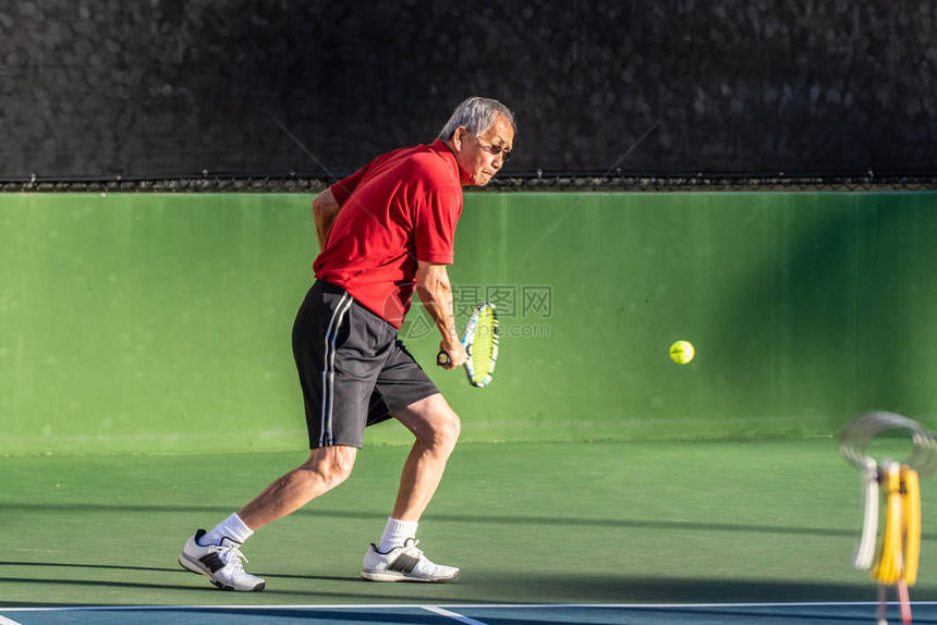 专注的老人在网球比赛中准备打反手时图片