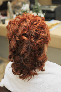发型师在棕色头发上为美发店后视线的妇女制图片