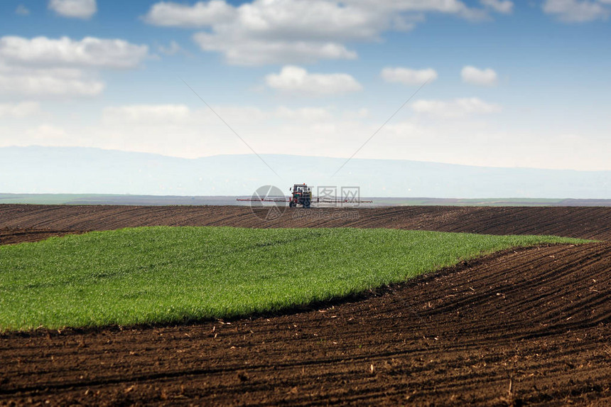 春季农业乡村景观中的拖拉机喷药田图片