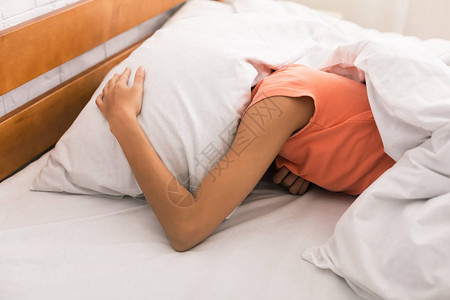 睡眠不足女人用枕头捂着头早上醒来背景图片