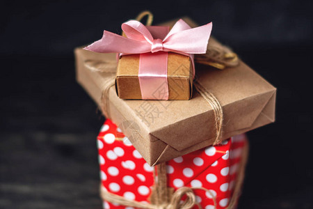 节日礼品盒包装在手工纸和深色木制背景上的红色圆点带礼物的漂图片