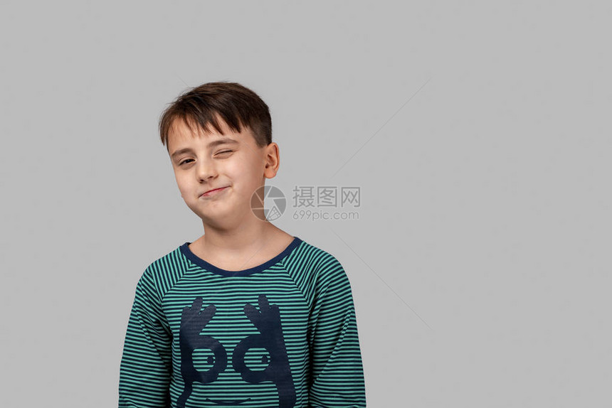 一个穿着绿色黑条纹T恤的小男孩站着咧嘴笑着图片