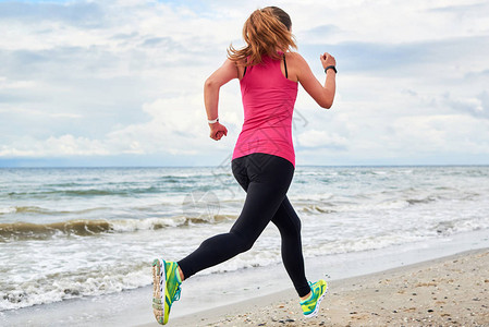 运动女子在海滩上奔跑的背影图片