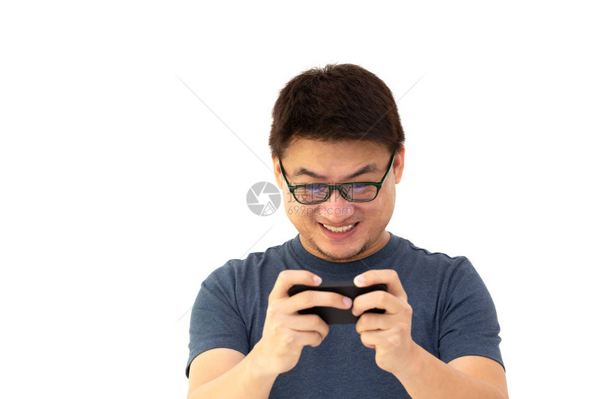 身穿深蓝色T恤衫戴着眼镜在手机上玩游戏的亚洲男子被白色背景孤立的照片描绘成一幅激图片