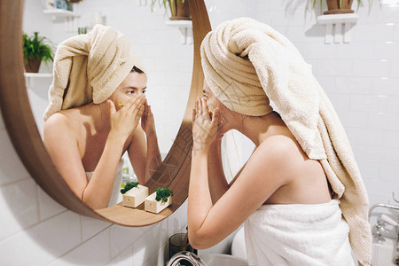 年轻快乐的女人用毛巾涂抹有机面部磨砂膏图片