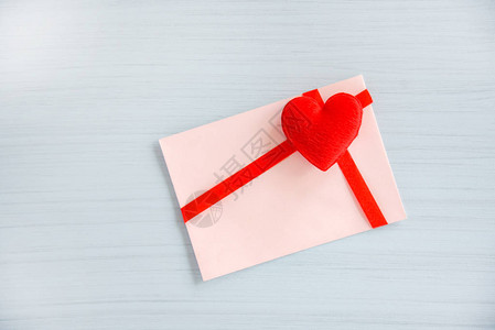 白色木质背景上饰有红丝带蝴蝶结和心形的礼品卡信封情书人节信卡或优图片