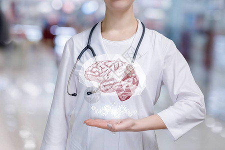 在医院背景模糊的年轻医生手上悬挂的心理健康大脑和齿轮机图片