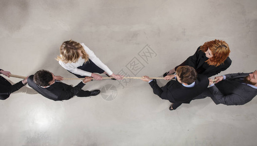 争斗的男女商人通过拉绳子竞争指挥图片