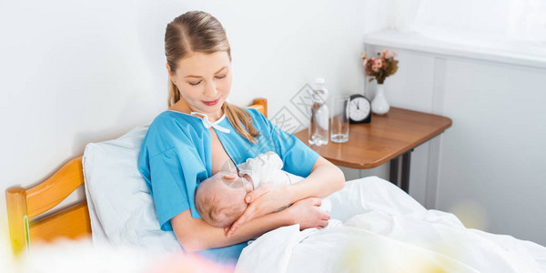 从高角度看年轻母亲在医院房间里微笑母乳喂养新生儿婴图片
