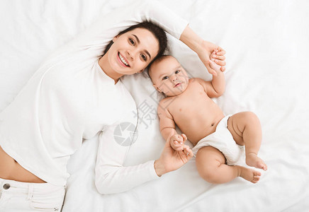 快乐的微笑的母亲和婴儿躺在家中图片