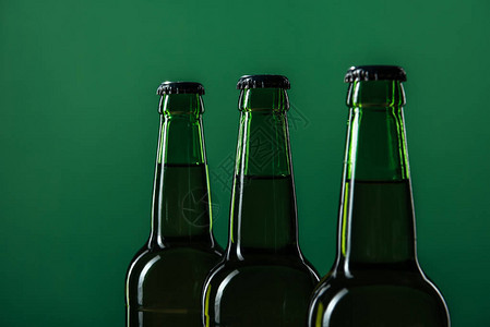 密闭的啤酒瓶孤立在绿色背景图片