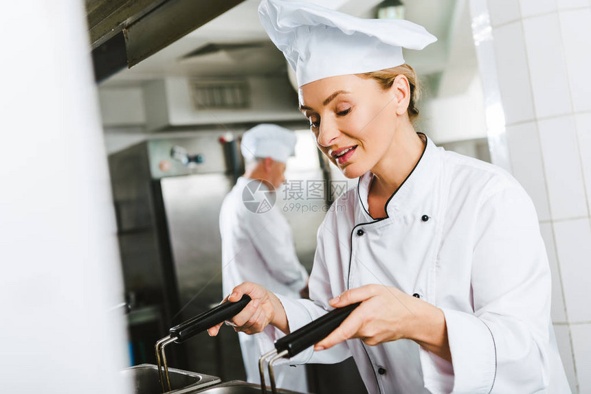 穿制服的漂亮女厨师在餐厅厨房做饭图片