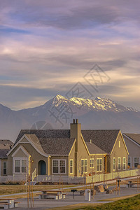 有白色尖桩篱栅的家与雄伟的山脉和多云的天空相映成趣图片
