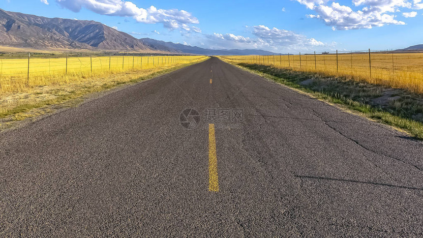 铺好的道路雄伟的山脉和天空与云彩在灿烂的蓝天下穿过雄伟的尼波山和犹他州北峰的铺砌道路这条路在一片广图片