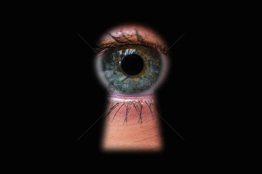 人的眼睛在门后透过一个关键孔图片