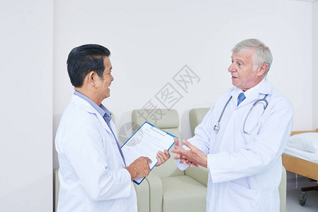 两名老年医生站在医院病房里交谈的侧视图图片