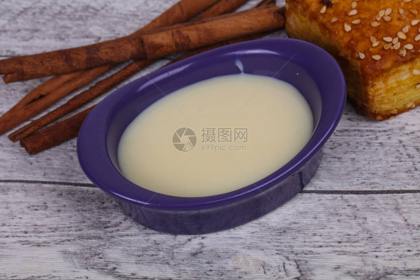 碗里的炼乳配上桂枝和糕点图片