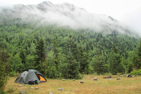 山上森林背景的帐篷和背包在雾中清晨一片阴云图片