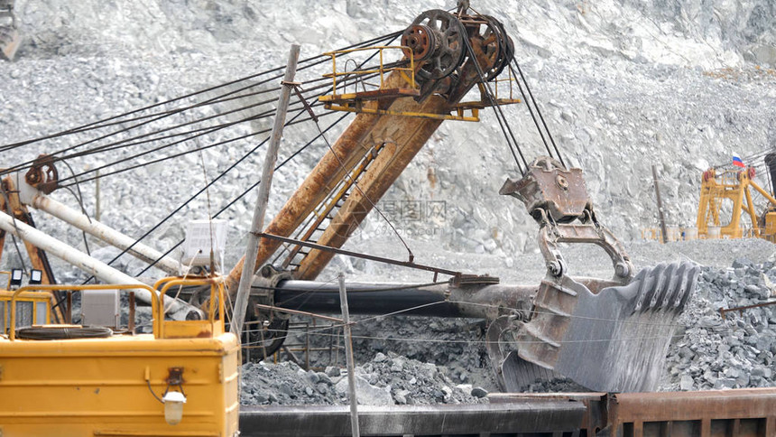 挖掘机和铁路与矿石挖掘机在露天矿坑的背景下装满了矿石轨道车采矿图片
