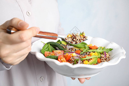女人吃健康的quinoa沙拉和盘子里图片