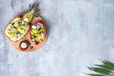 外表水果沙拉在半只龙果和菠萝里放在圆木板图片