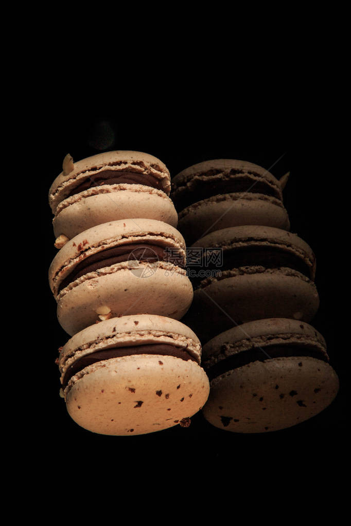 三条花生马卡龙巧克力填充在黑色镜面背景和反射图片