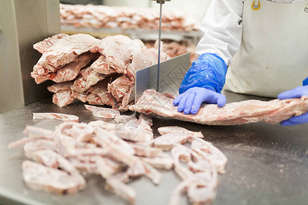 切肉室工人在电动皮带切割机上切一块肉背景图片