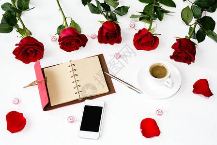 笔和一束红芳香玫瑰的花束在光背图片