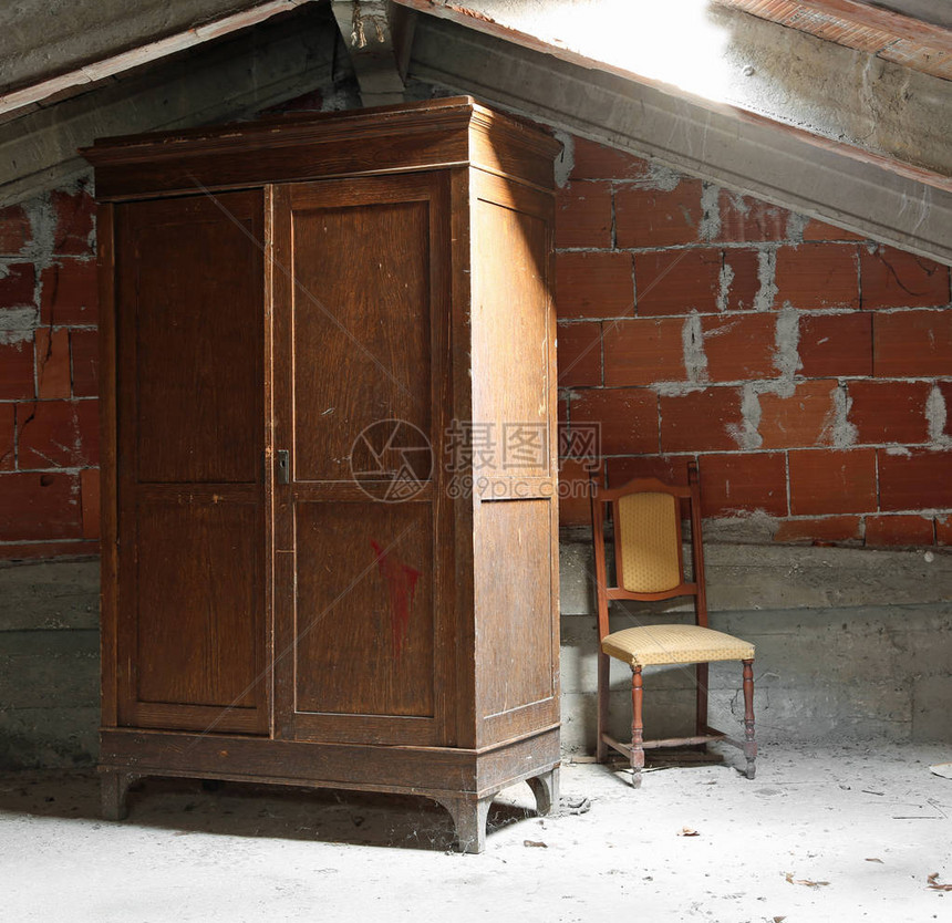 古老的木衣柜和破碎的椅子在灰尘弥漫的阁楼用图片