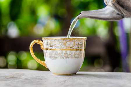 用水壶把茶倒在木桌上杯茶很漂亮图片
