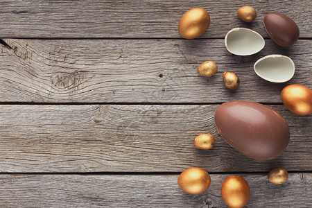 巧克力和金色的复活鸡蛋在木制背图片