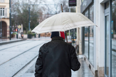 米卢斯背影在街上拿着雨伞行走的男子肖像背景