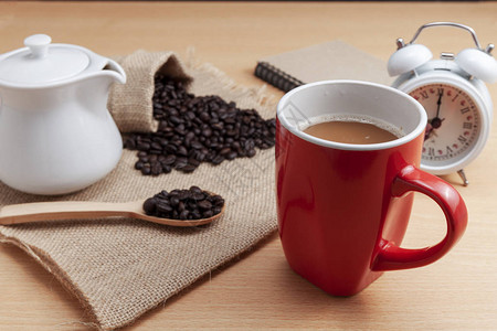 红咖啡杯咖啡豆和白闹钟图片