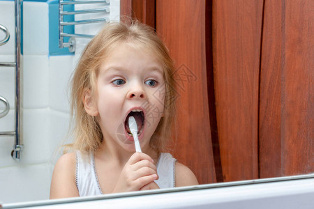 小女孩在镜子里刷牙的倒影图片