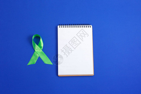 浅绿色丝带和蓝色背景上的打开笔记本肝癌淋巴瘤意识心理健康意识医疗保图片