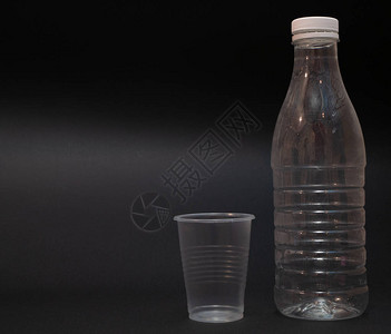 黑色暗底背景的空塑料瓶和杯子图片