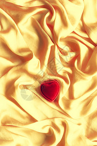 金色丝绸上的红色心形珠宝礼盒背景图片