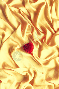金色丝绸上的红色心形珠宝礼盒图片