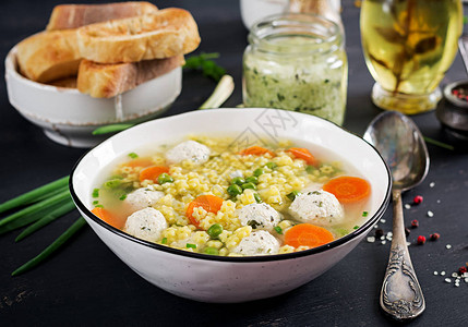 意大利肉丸汤和Stelline无麸质意大利面在黑桌上的碗里饮食汤宝图片
